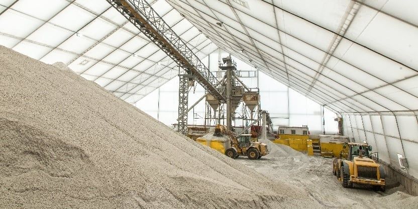 Covered industrial salt storage barn with loaders and a large salt pile